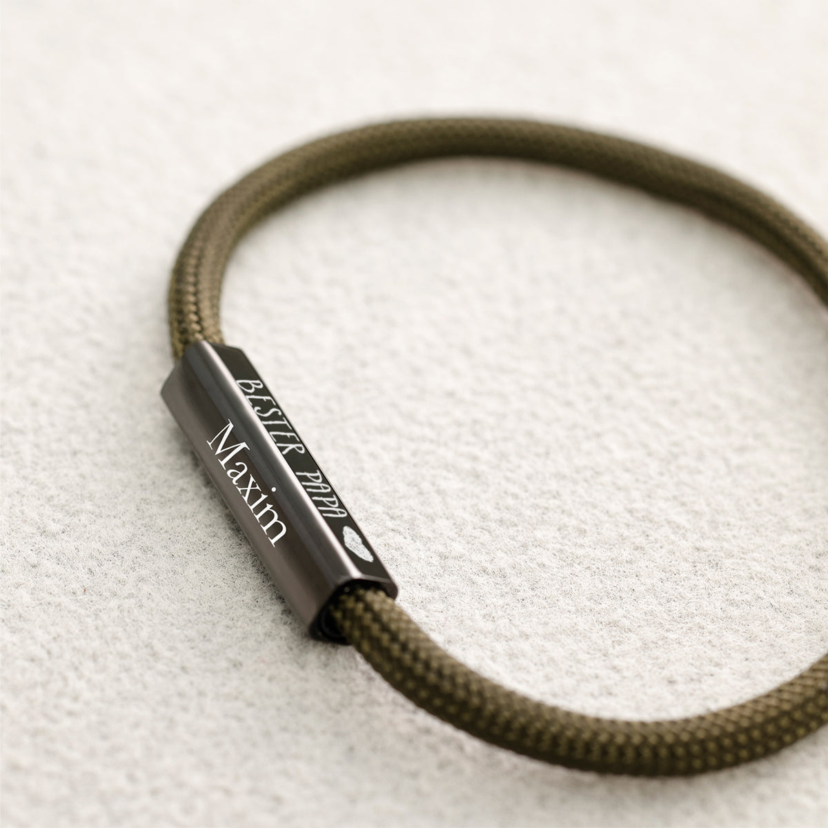 Graviertes Plättchen mit Text 'Bester Papa' und Name 'Maxim' auf olivgrünem Armband