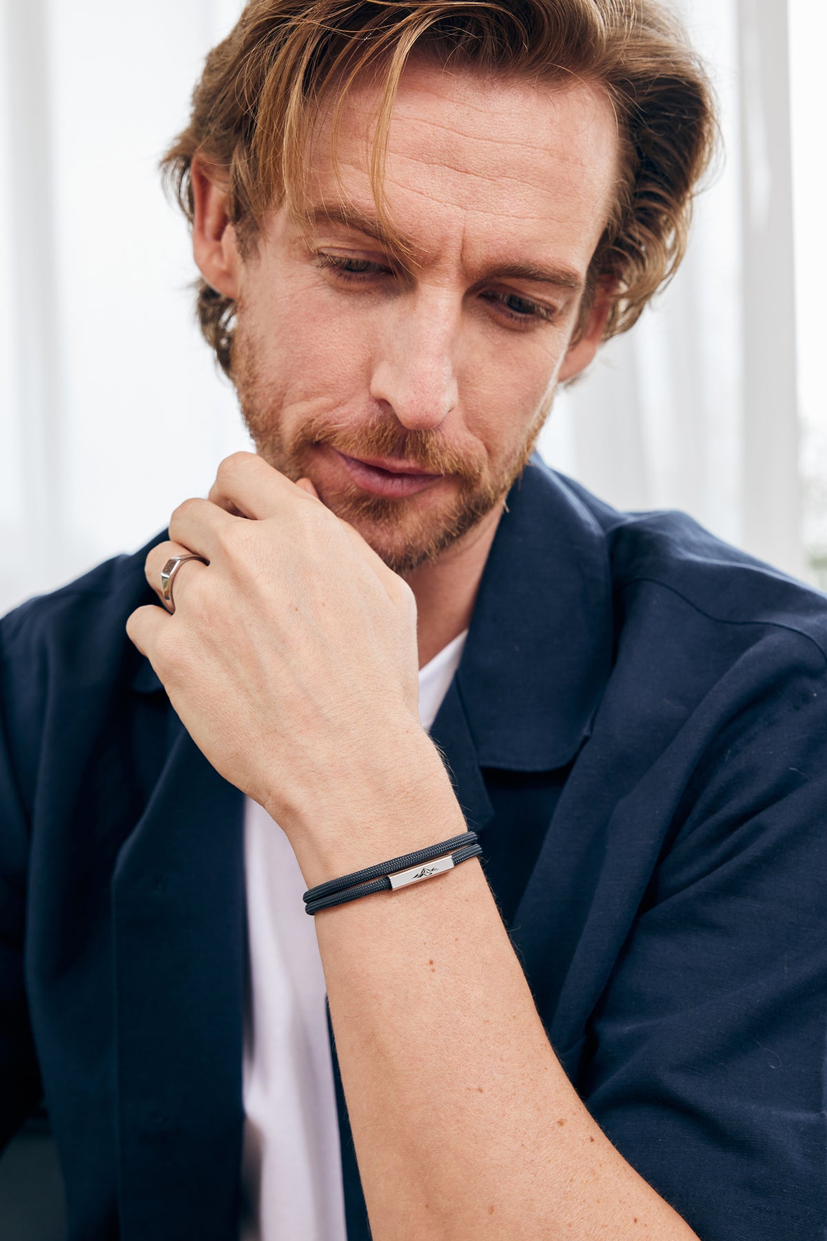 Mann trägt schwarzes Segeltau-Armband mit graviertem Verschluss, Ring an der anderen Hand