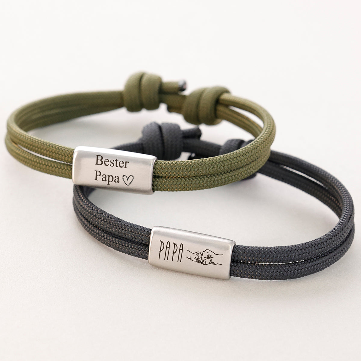 Zwei Papa Armbänder in Oliv und Anthrazit – graviert mit 'Bester Papa' und 'Papa' mit Faustgruß-Symbol