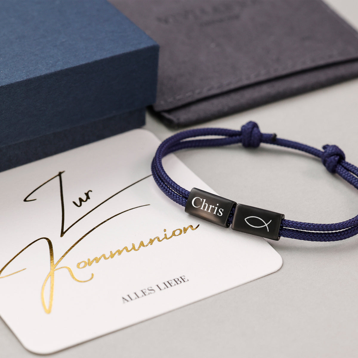 Segeltau Armband mit Wunschgravur in Blau neben Grußkarte 'Zur Kommunion' und Geschenkbox