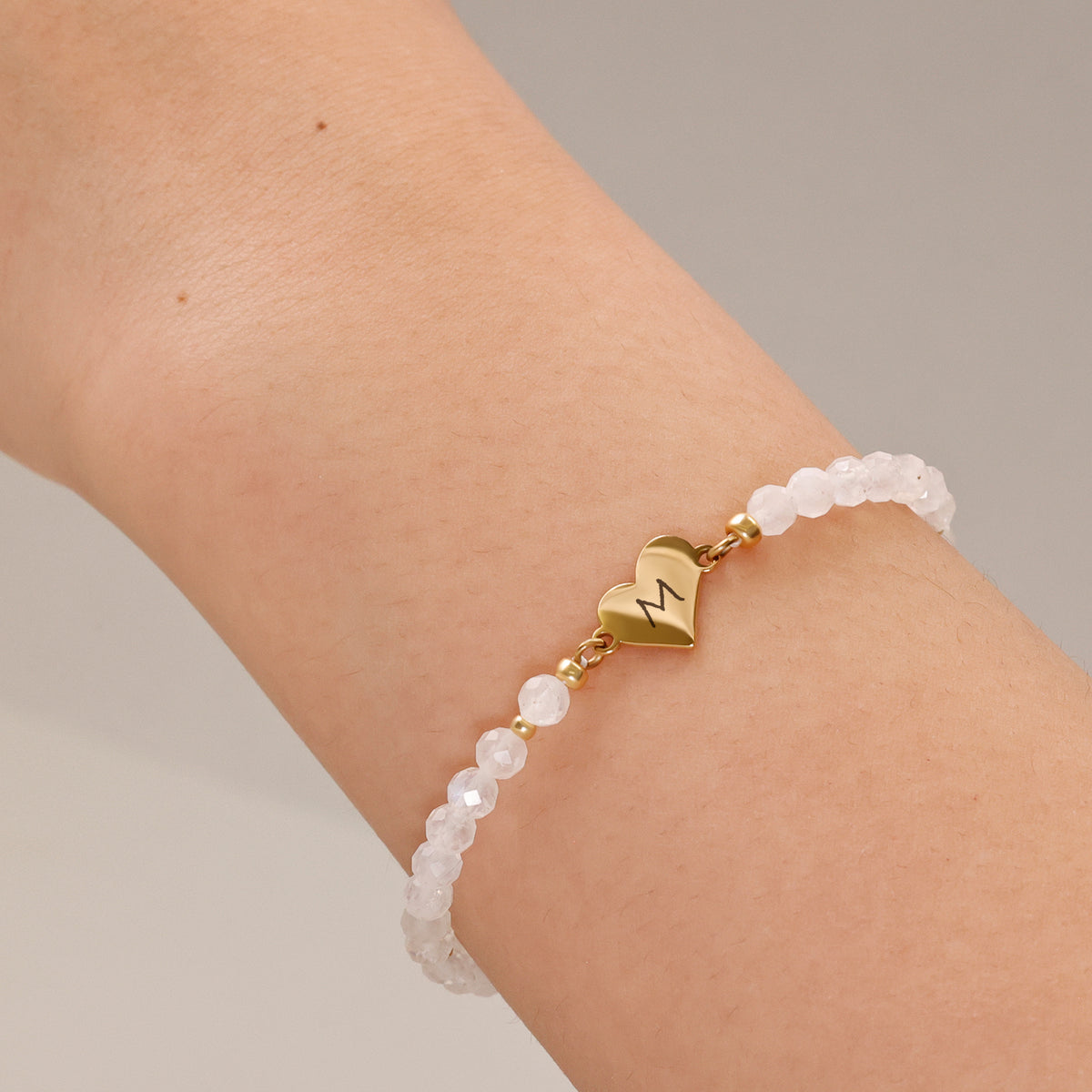 Frau trägt Herz-Armband mit Mondstein am Handgelenk – Herzanhänger mit graviertem Initial