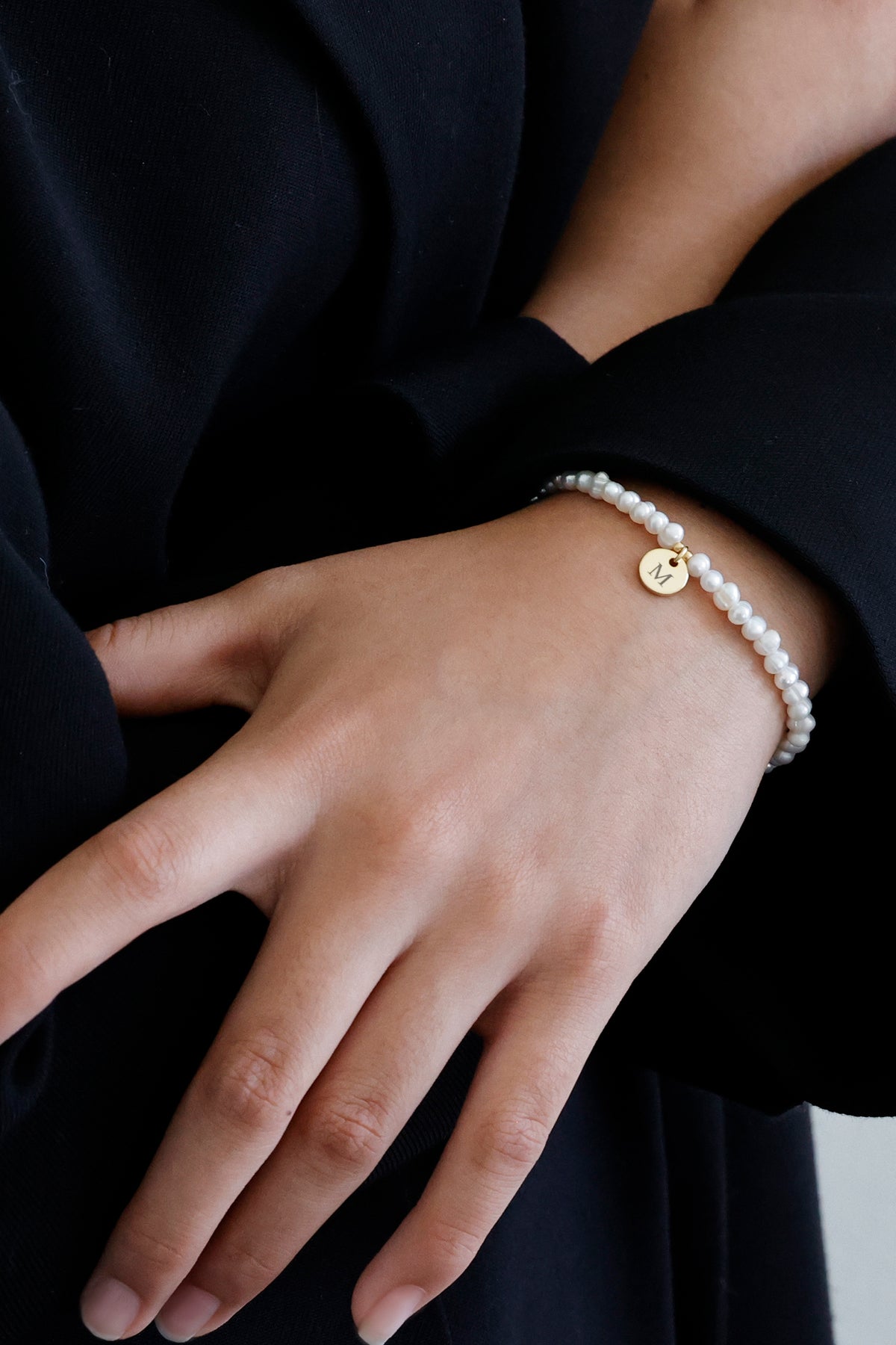 Süßwasserperlen Armband mit goldenem Gravuranhänger 'M' – Nahaufnahme am Handrücken