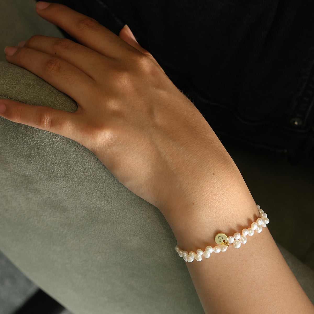 Süßwasserperlen Armband am Handgelenk, Nahaufnahme mit goldenem M-Plättchen